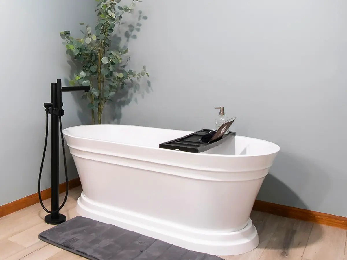 Freestanding white bathtub with black fixtures, set against a minimalist bathroom interior.